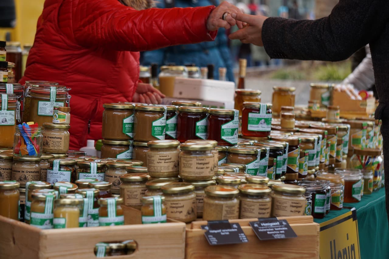 Labeled jars of honey arranged for sale at a small farmers market stand
