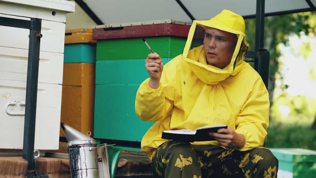 Beekeeper writing dated hive notes in a notebook beside the hives